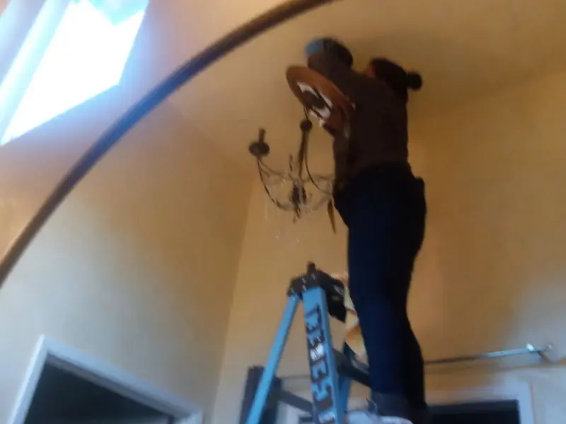 Electrician installing a chandelier in a Titusville residence